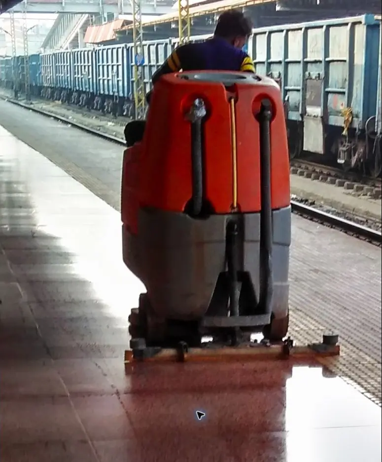 Operador usando máquina de limpeza de piso em uma grande instalação