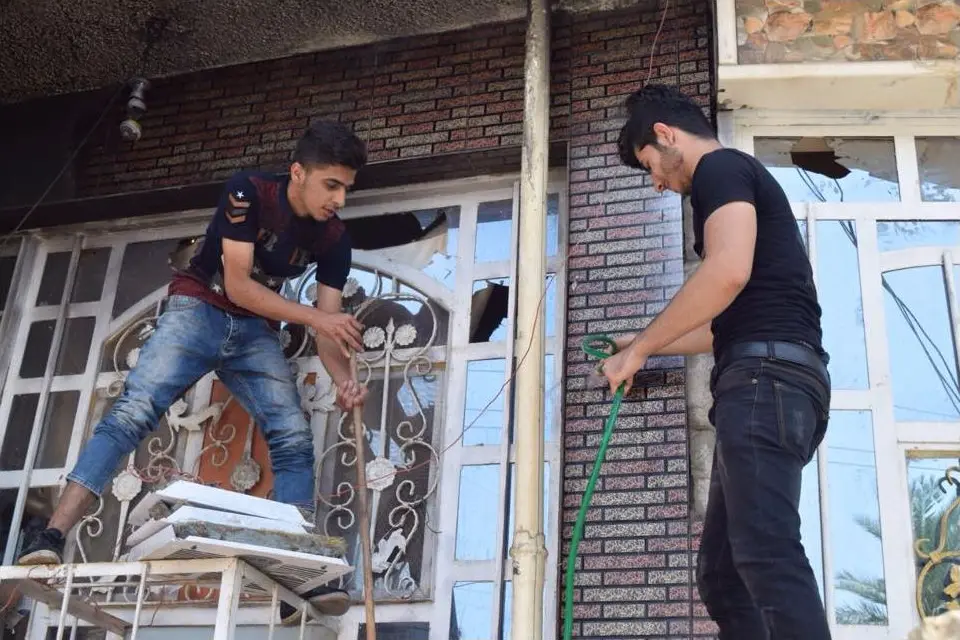 Pessoas removendo resíduos de uma construção após um incêndio