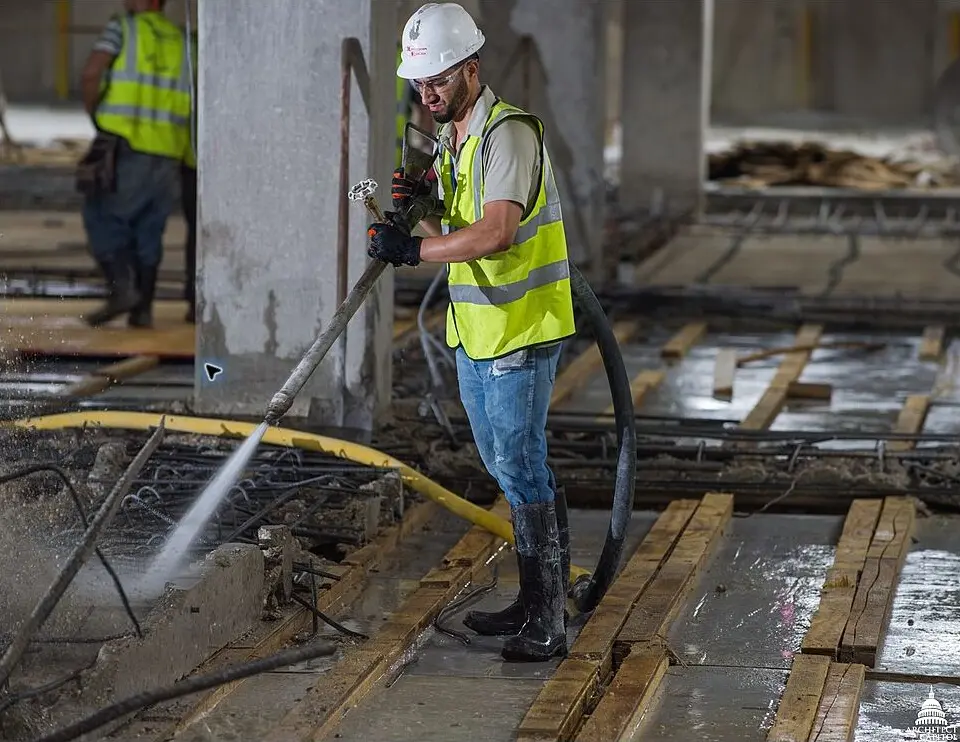 Trabalhador limpando uma área em obra com lavadora de alta pressão